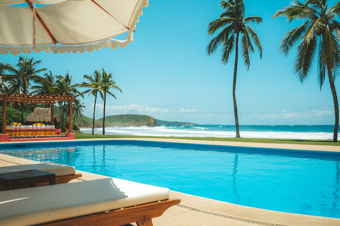 a large swimming pool next to a lush green beach