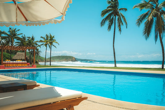 a large swimming pool next to a lush green beach