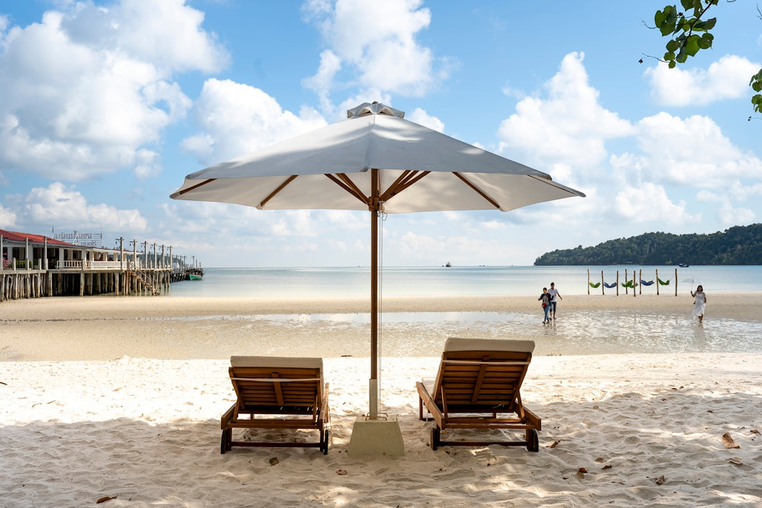 a couple of chairs sitting under an umbrella on a beach