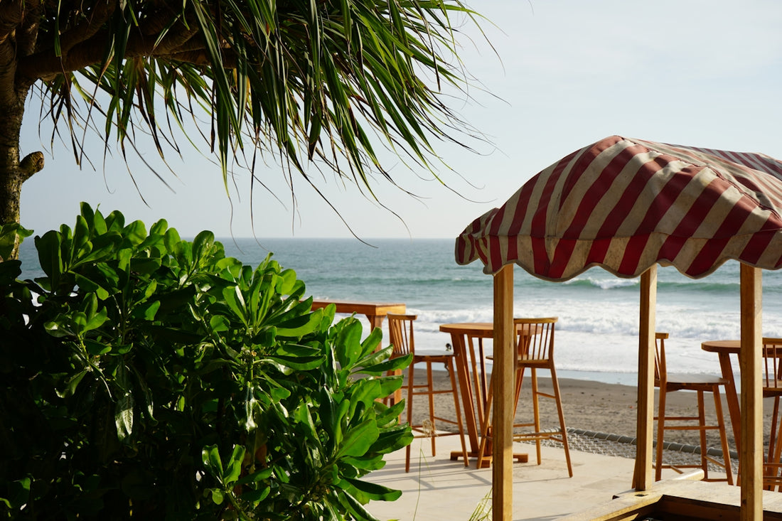 an umbrella and chairs on a beach with the ocean in the background