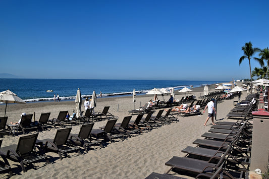 Beach with many lounge chairs and clear blue sky.